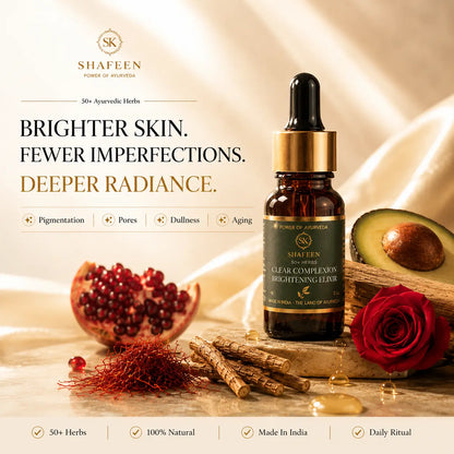 Shafeen Ayurveda Clear Complexion Brightening Elixir in an amber glass dropper bottle, styled with a pomegranate, avocado, red rose, and herbal roots on a draped beige fabric background with promotional text.