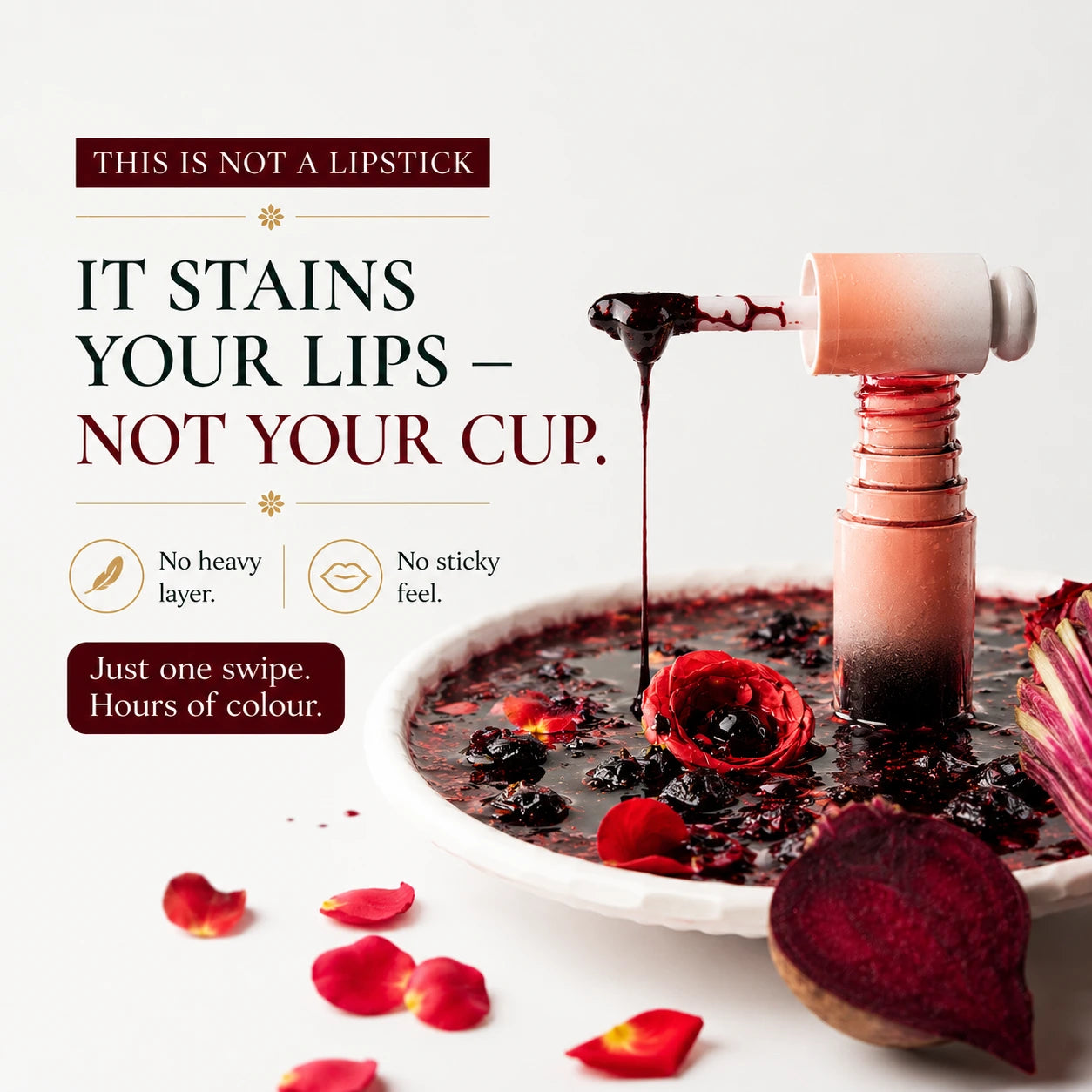 A cosmetic product bottle and wand are shown dripping dark berry-colored liquid onto a plate of red beet and rose petals, with text reading 'THIS IS NOT A LIPSTICK' and 'IT STAINS YOUR LIPS – NOT YOUR CUP.' on a clean white background.